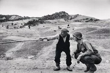 Un siciliano spiega ad un ufficiale americano quale strada hanno percorso i tedeschi vicino a Troina, Sicilia, 4-5 agosto 1943 @Robert Capa @ International Center of Photography/Magnum